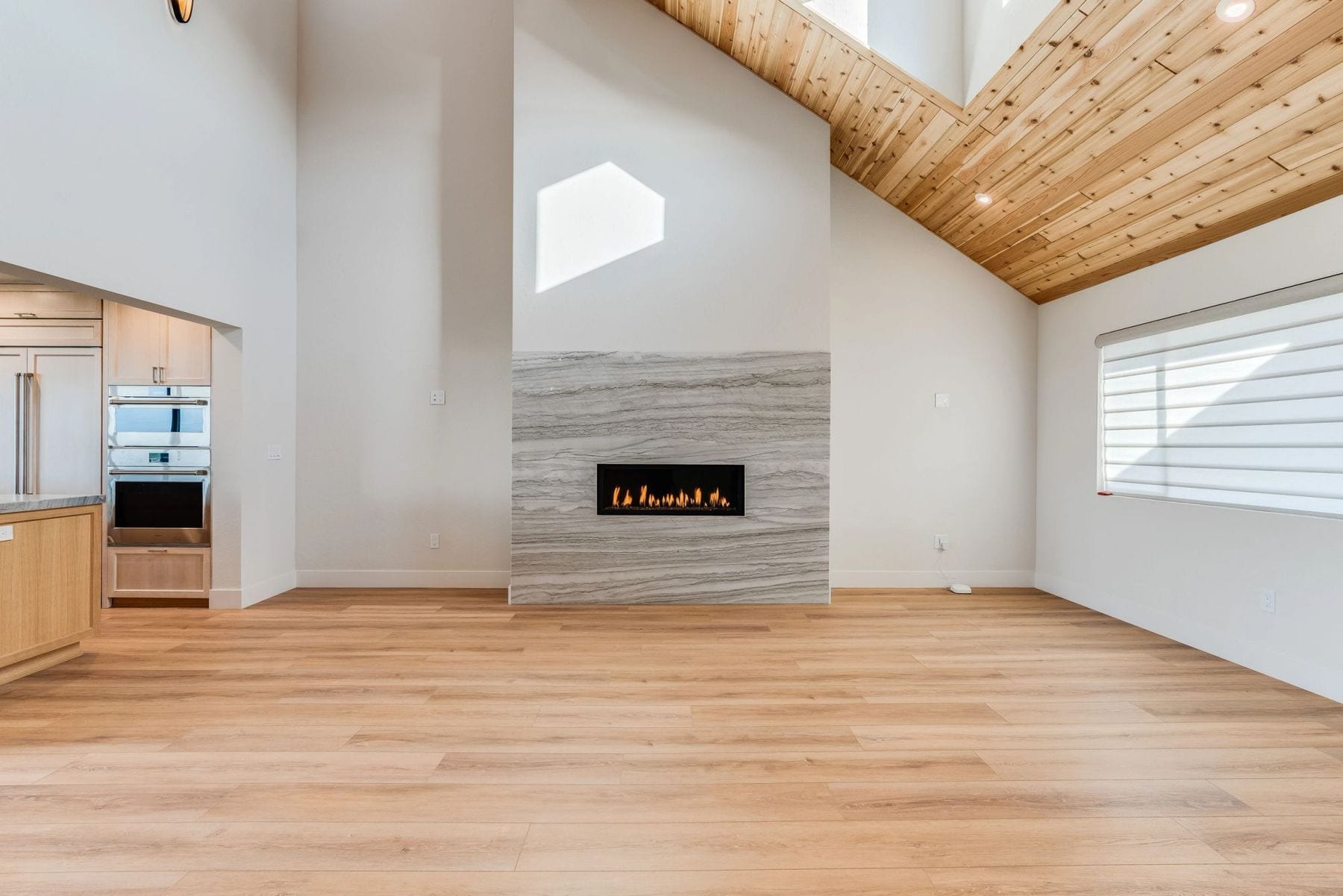Living room with a vaulted wood-plank ceiling and a linear stone fireplace.