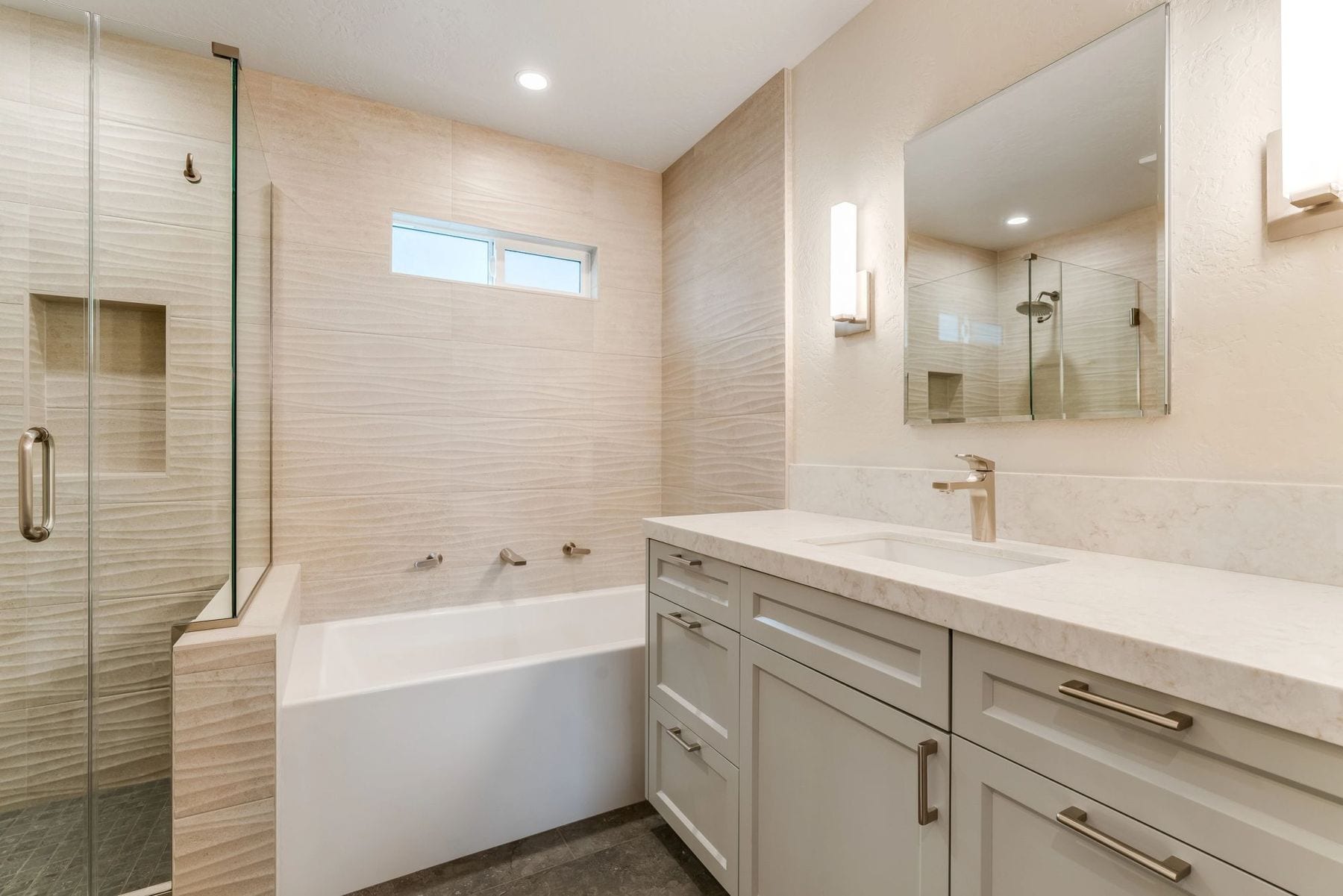 Bathroom with a soaking tub, textured wall tile, and a glass shower.