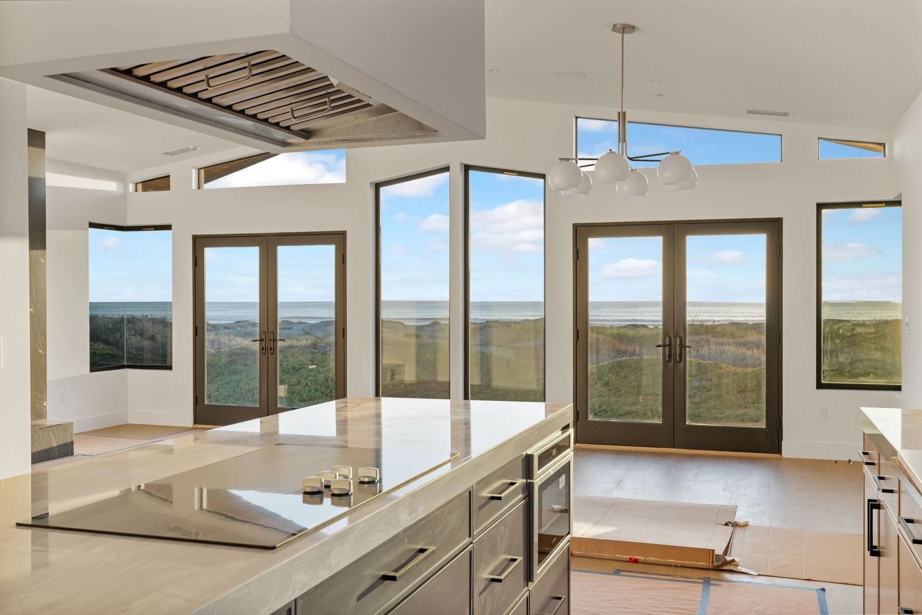 Kitchen and living area opening to dunes and the ocean through a wall of glass.