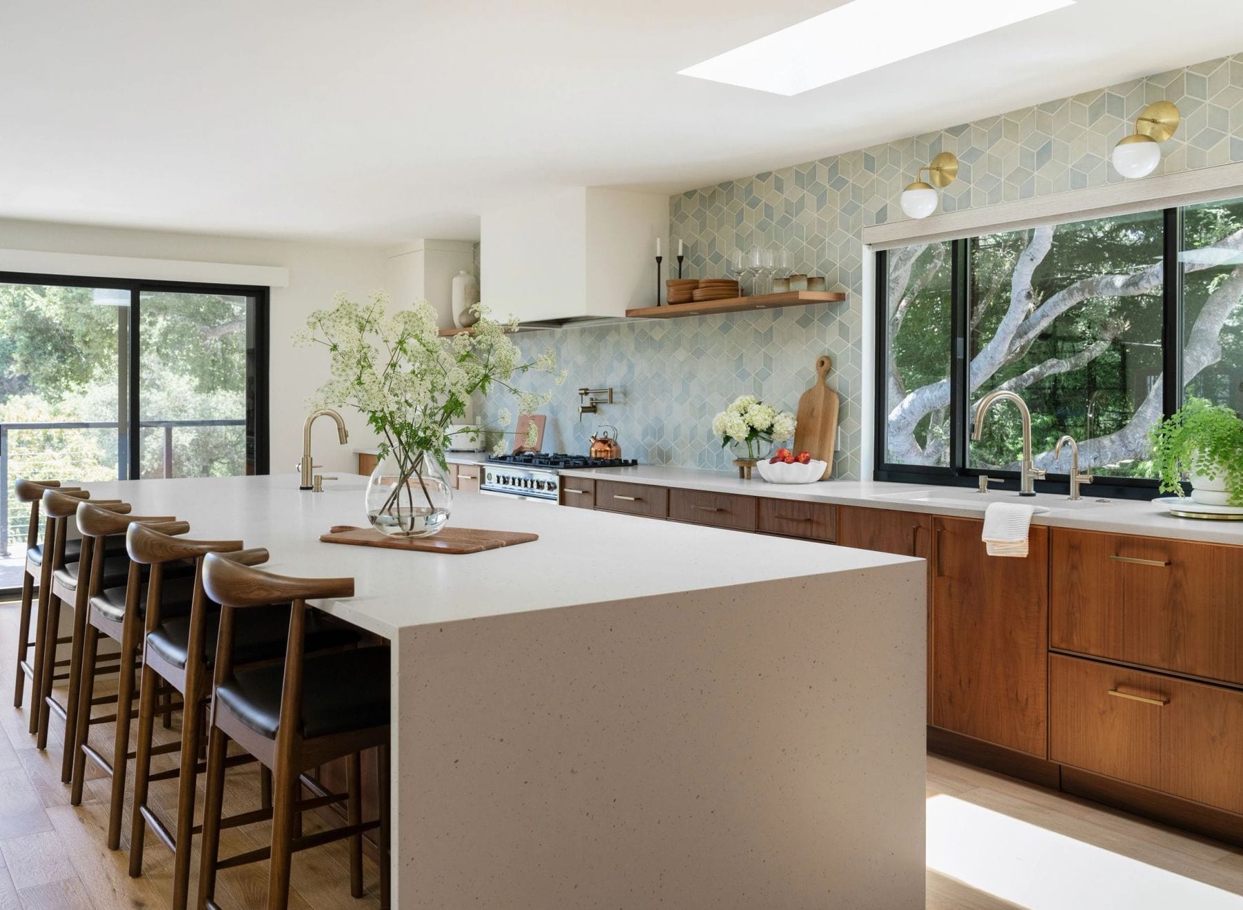 Kitchen with a white waterfall island, wood cabinets, and geometric tile backsplash.