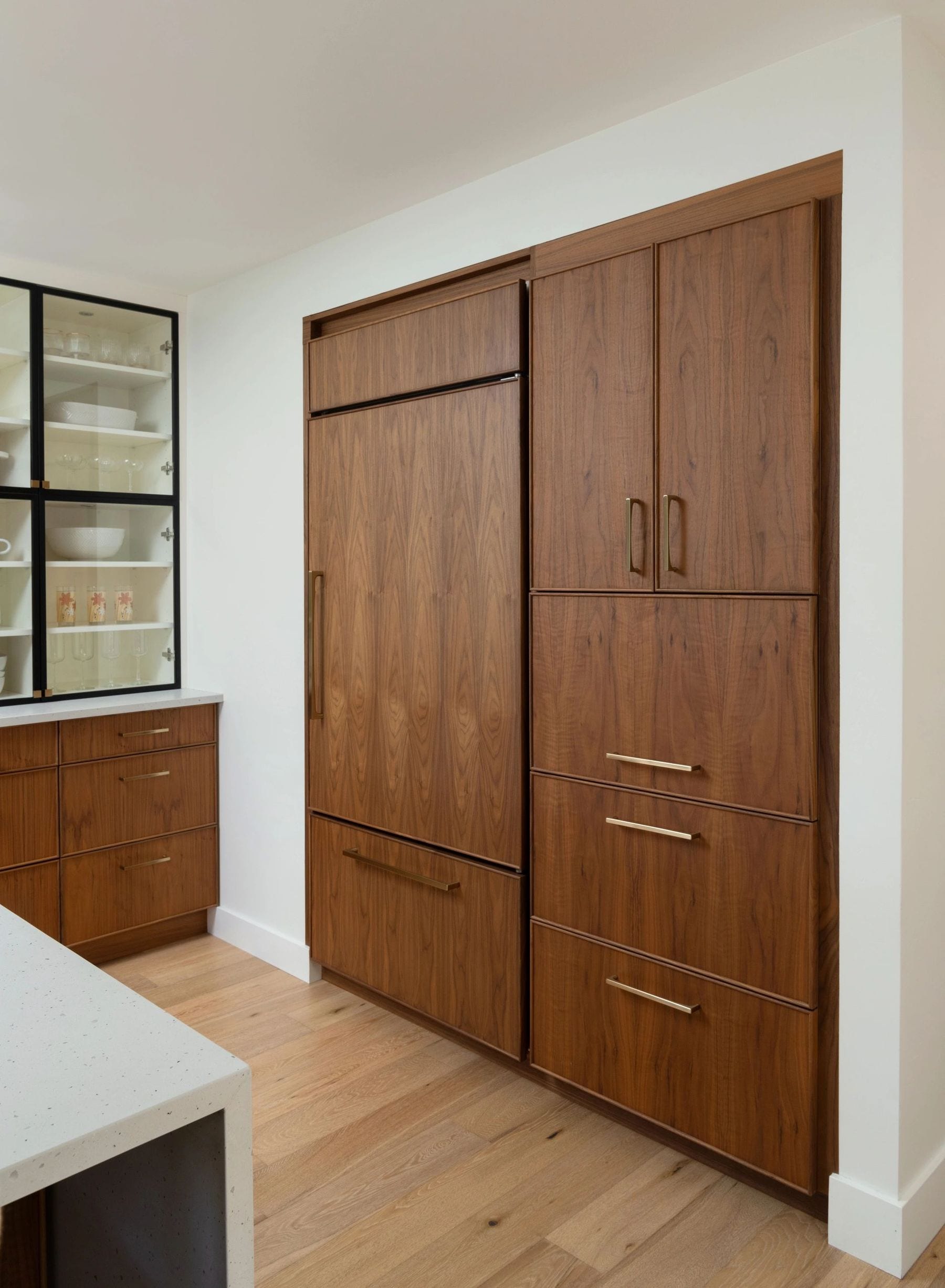 Floor-to-ceiling wood kitchen cabinets with a glass-front display case.
